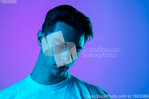 Image of Handsome caucasian man\'s portrait isolated on purple studio background in neon light, monochrome