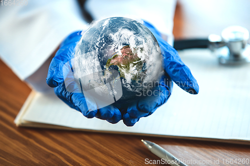 Image of Doctor holding a world globe in hands, concept of world health, supporting