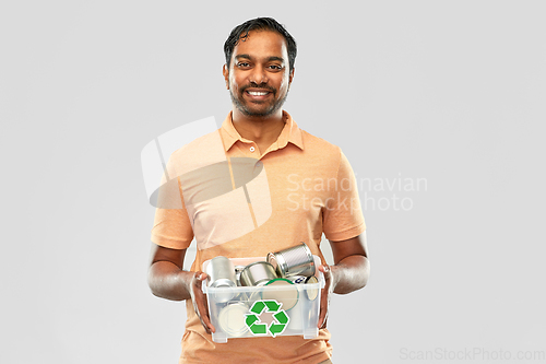 Image of smiling young indian man sorting metallic waste