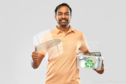 Image of smiling young indian man sorting metallic waste