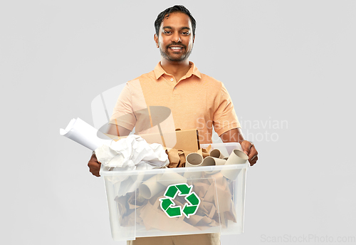 Image of smiling young indian man sorting paper waste