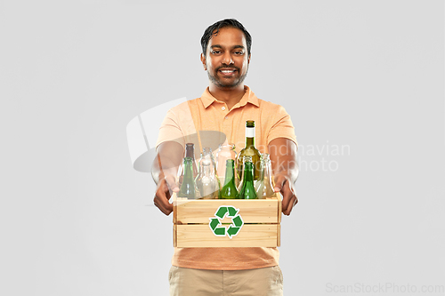 Image of smiling young indian man sorting glass waste