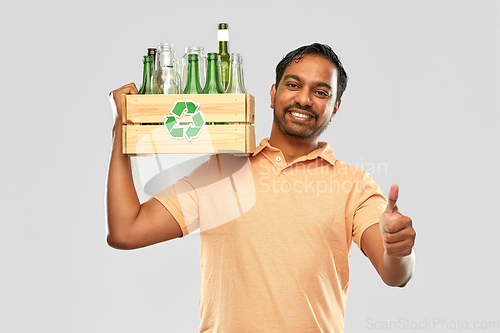 Image of smiling young indian man sorting glass waste