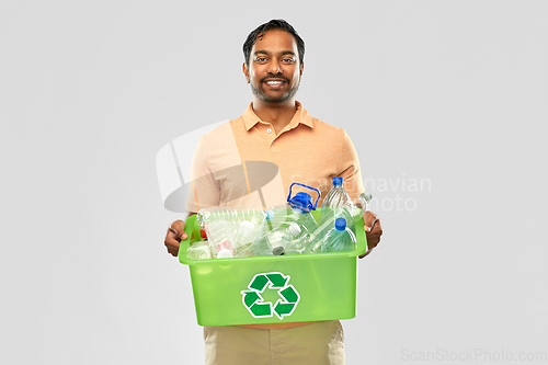 Image of smiling young indian man sorting plastic waste