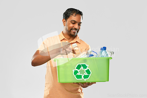 Image of smiling young indian man sorting plastic waste