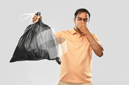 Image of indian man holding stinky trash bag