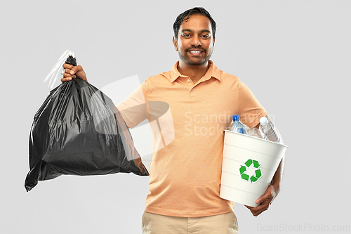 Image of smiling indian man sorting paper and plastic waste