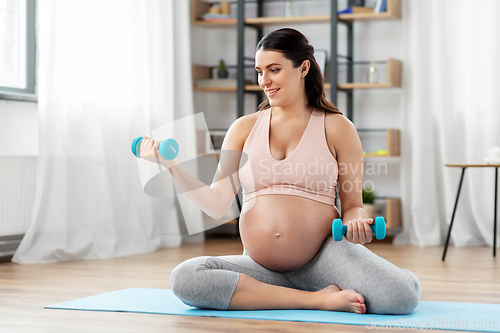 Image of pregnant woman with dumbbells doing sports at home