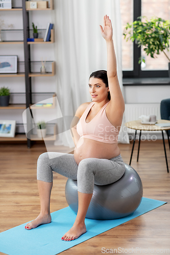 Image of pregnant woman exercising on fitness ball at home