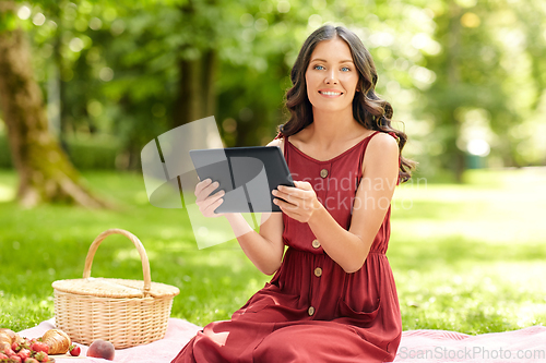 Image of happy woman with tablet computer on picnic at park