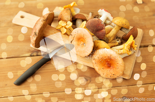 Image of edible mushrooms on wooden cutting board and knife