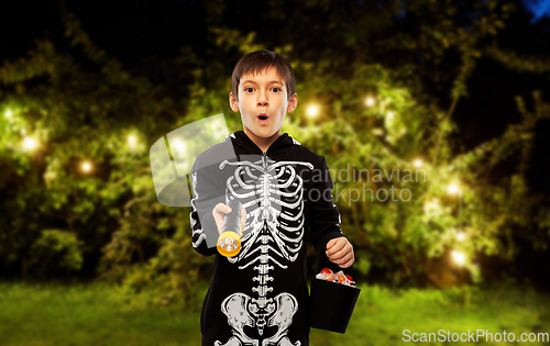 Image of boy in halloween costume with candies and torch