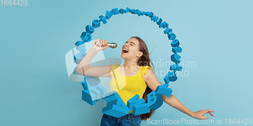 Image of Girl shouting, singing with speaker, microphone on studio background. Sales, offer, business, cheering fun concept.