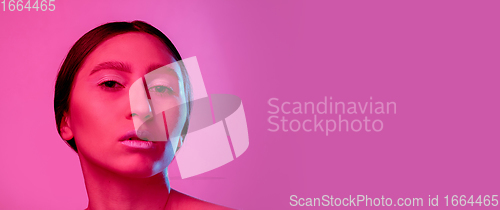 Image of Beautiful east woman portrait isolated on pink studio background in neon light, monochrome