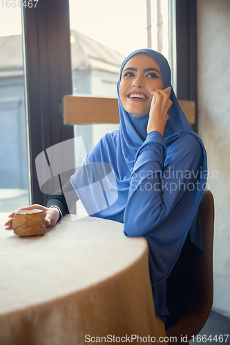 Image of Beautiful arab woman meeting at cafe or restaurant with friend, spending time with cup of tea