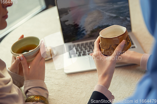 Image of Close up female hands pouring tea in cup at restaurant or cafe, daily lifestyle