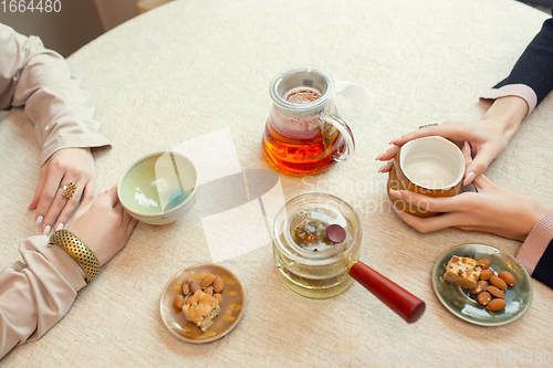 Image of Close up female hands pouring tea in cup at restaurant or cafe, daily lifestyle