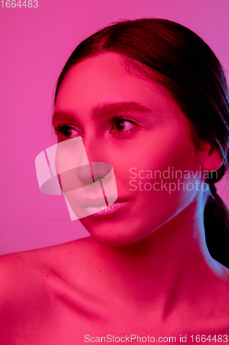 Image of Beautiful east woman portrait isolated on pink studio background in neon light, monochrome