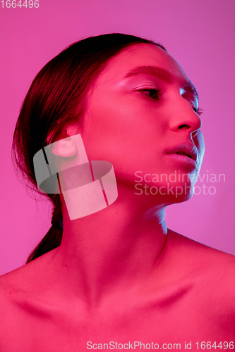 Image of Beautiful east woman portrait isolated on pink studio background in neon light, monochrome