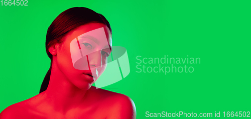 Image of Beautiful east woman close up portrait isolated on green background in red neon light
