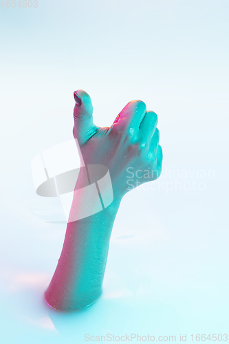 Image of Close up female hand gesturing from the milk bath with soft glowing in neon light