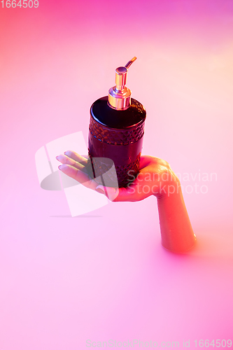 Image of Close up female hand gesturing from the milk bath with soft glowing in neon light