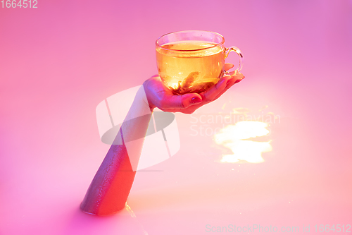 Image of Close up female hand gesturing from the milk bath with soft glowing in neon light