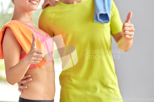 Image of close up of happy couple showing thumbs up in gym