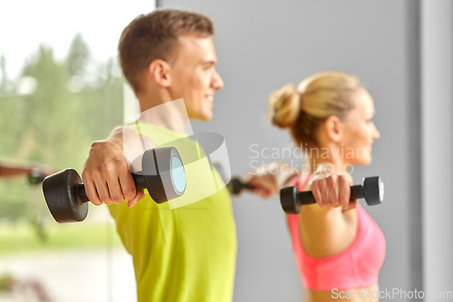 Image of close up of smiling woman with dumbbell in gym