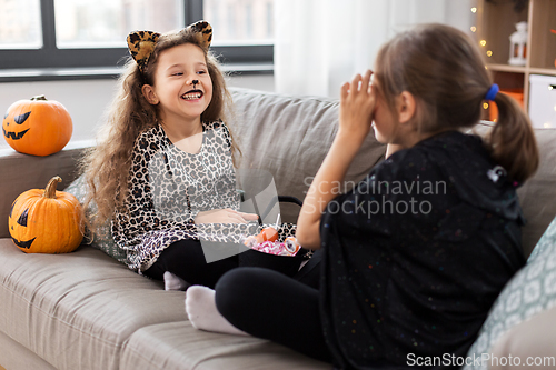 Image of girls in halloween costumes with candies at home