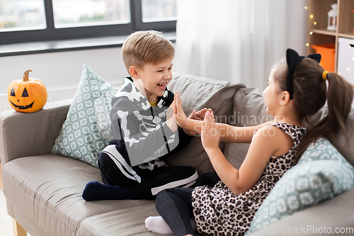 Image of kids in halloween costumes playing game at home