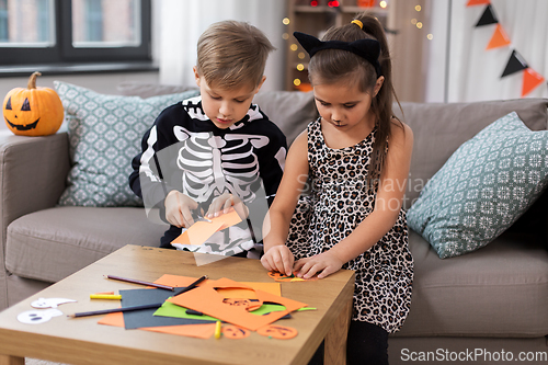 Image of kids in halloween costumes doing crafts at home