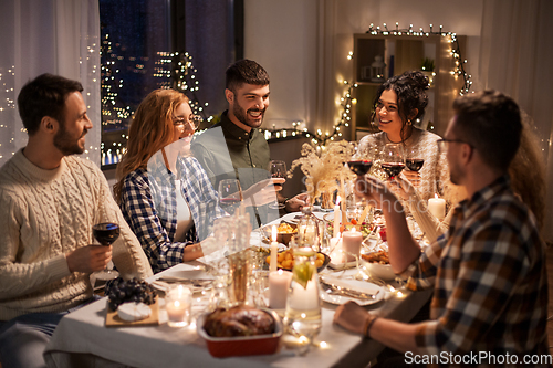 Image of happy friends drinking red wine at christmas party