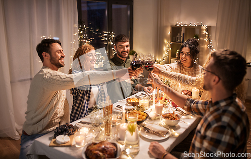 Image of happy friends drinking red wine at christmas party