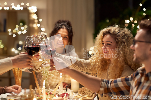 Image of happy friends drinking red wine at christmas party