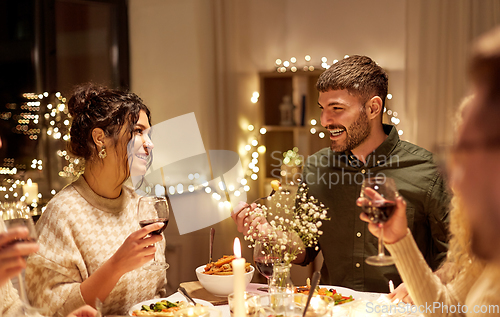 Image of happy friends drinking red wine at christmas party