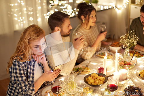 Image of woman with smartphone at dinner party with friends