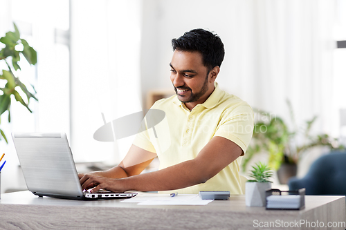 Image of man with laptop and papers working at home