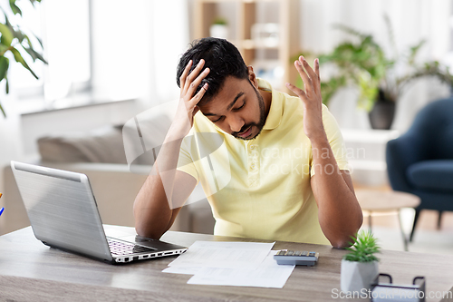 Image of man with calculator and papers working at home