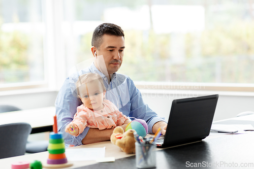 Image of father with baby working at home office