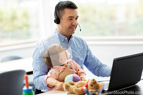 Image of father with baby working on laptop at home office