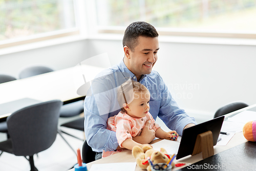 Image of father with baby working on tablet pc at home