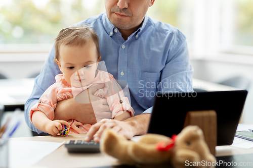 Image of father with baby working at home