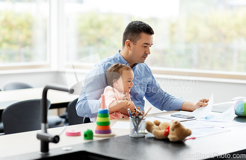 Image of father with baby working at home office