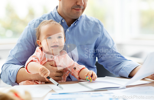 Image of father with baby working at home office