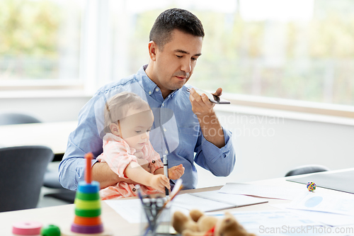 Image of father with baby and phone working at home office