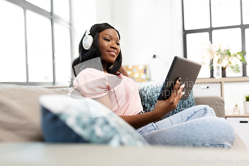 Image of woman with tablet pc listening to music at home