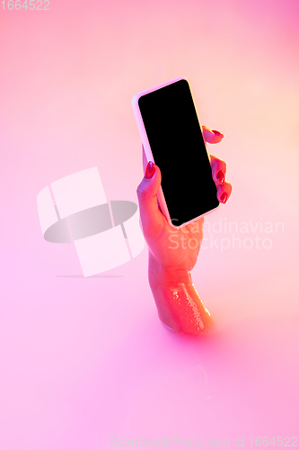 Image of Close up female hand gesturing from the milk bath with soft glowing in neon light