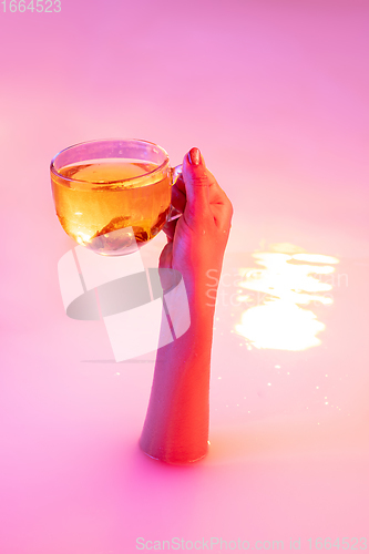 Image of Close up female hand gesturing from the milk bath with soft glowing in neon light