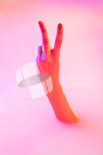 Image of Close up female hand gesturing from the milk bath with soft glowing in neon light